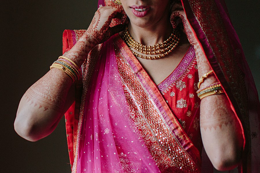 Indian bride getting dressed with traditional indian wedding gown