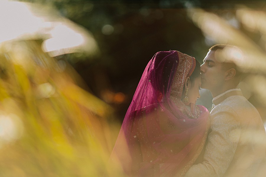 Artistic and romantic bride and groom portrait wearing traditional Indian wedding outfits